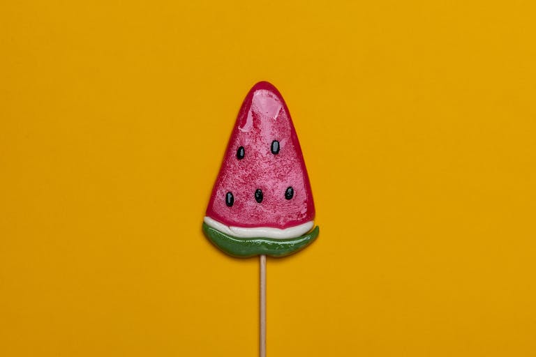 BPop Up Surfing right watermelon candy lollipop with a vibrant yellow backdrop, perfect for summer themes.