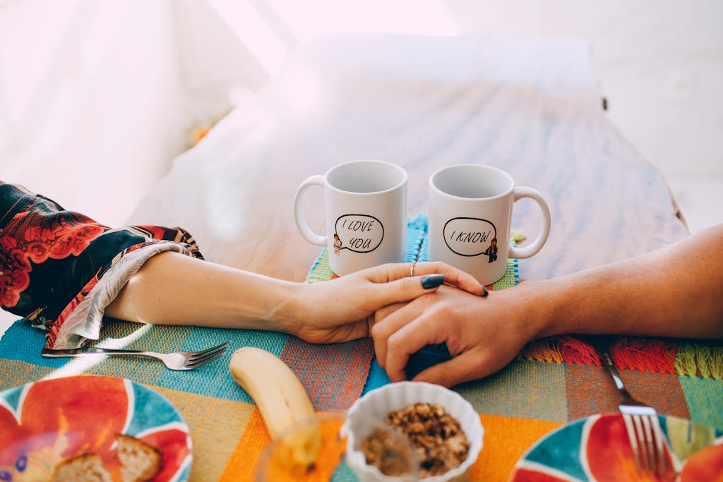 Cheerphones A cozy breakfast scene with two mugs, holding hands, and a colorful table setting.