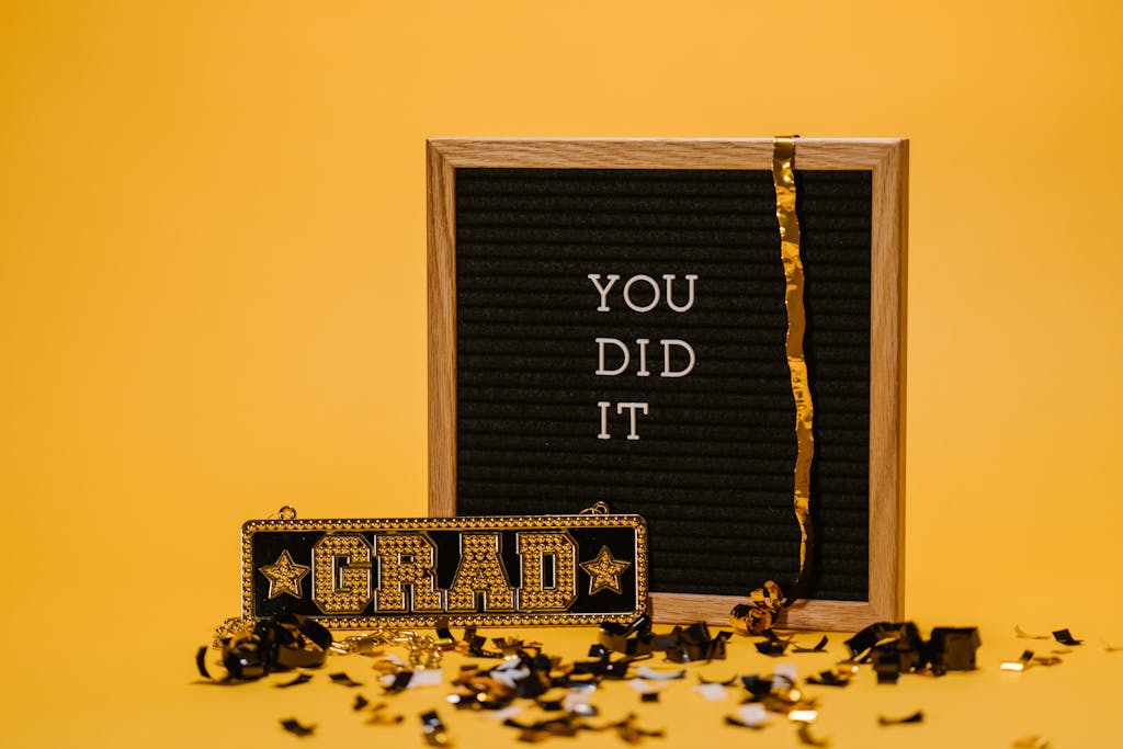 Cheerphones A graduation celebration with a letter board and confetti on a vibrant yellow background.