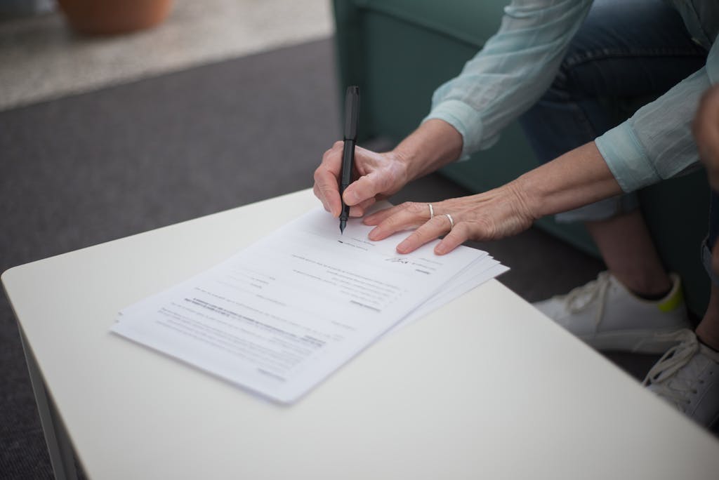 Bolly4u Me A person signing important legal documents on a table, emphasizing business and professionalism.