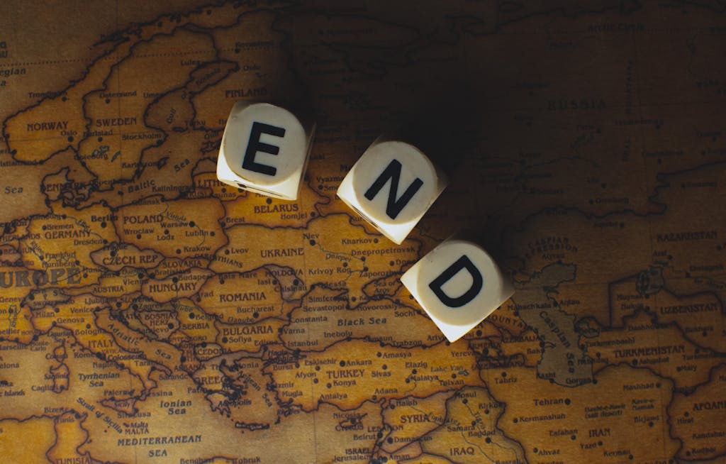 Serlig: Close-up of dice spelling 'END' placed on a map of Europe, symbolizing finish line or travel completion.