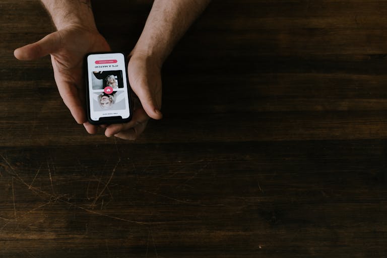 Gonzay Close-up of hands holding a smartphone with a social media app open on a wooden table.