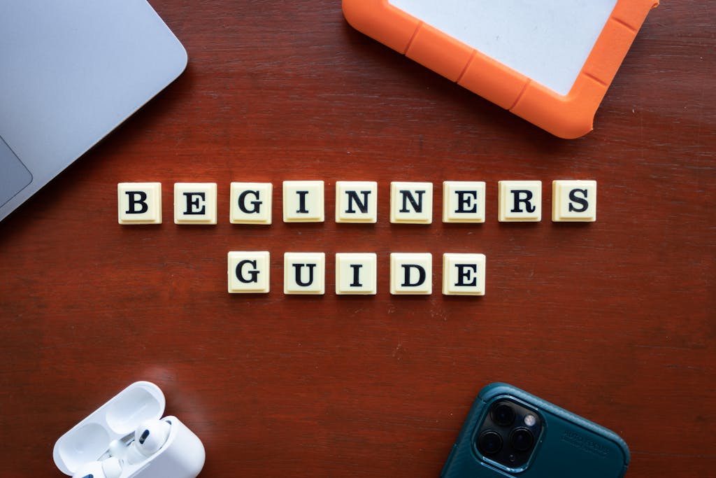 Buscrs Creative flat lay of gadgets and 'Beginners Guide' text on wooden table.