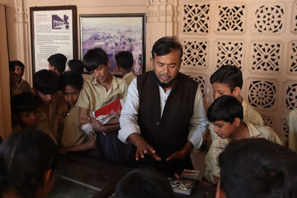 Dainikshiksha.com Group of school children on a heritage tour with a guide in an Indian museum.