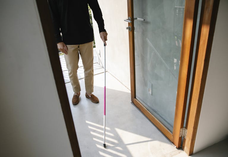 Impupdates.comwow Independence Person with visual impairment using a cane to enter a house, symbolizing independence.