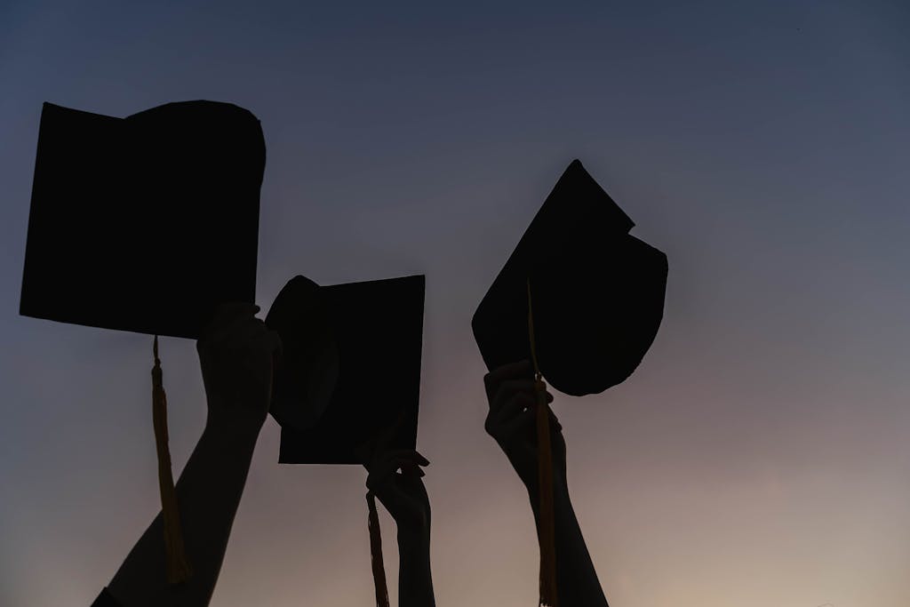 Pxless Silhouetted graduates celebrating at dusk with caps held high, symbolizing success and new beginnings.