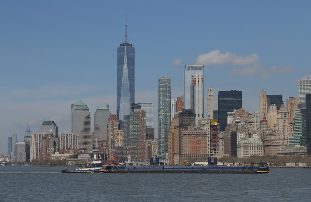 Latest News Today Stunning view of the New York City skyline featuring the iconic One World Trade Center across the Hudson River.