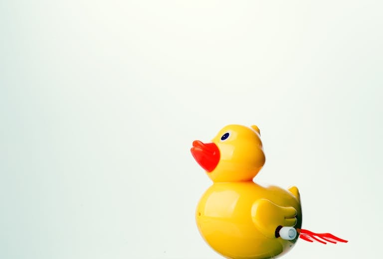 Newstook A bright yellow rubber duck toy against a plain white background with ample copy space.