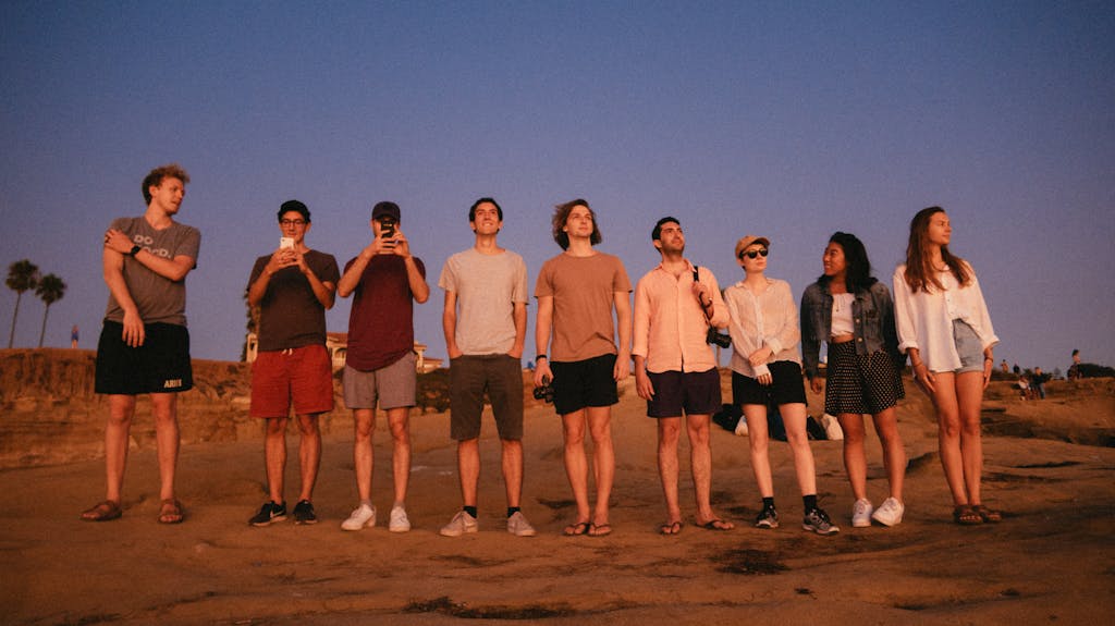 juntosseguros A diverse group of young adults standing together at a beach during sunset. Capturing the essence of friendship.