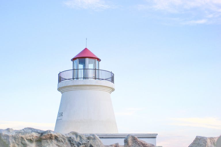 Shop Sunnylife Giant Jumbling Tower A picturesque lighthouse stands tall under a vibrant blue sky, offering a sense of tranquility.