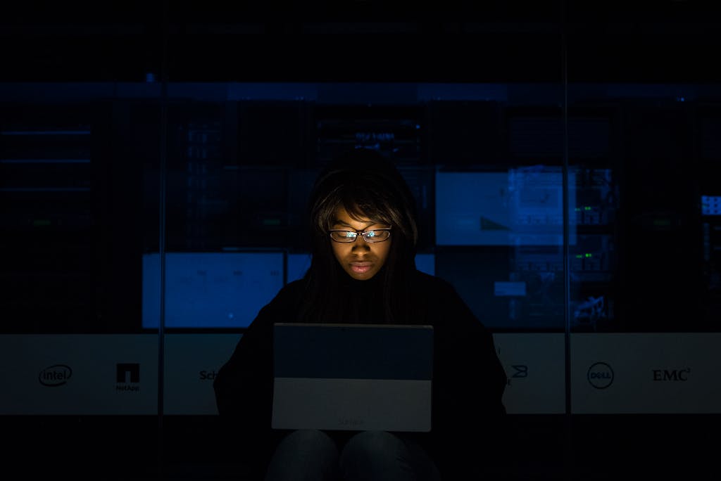 What’s On Tech A woman deeply engrossed in programming on a laptop at night in a data center.