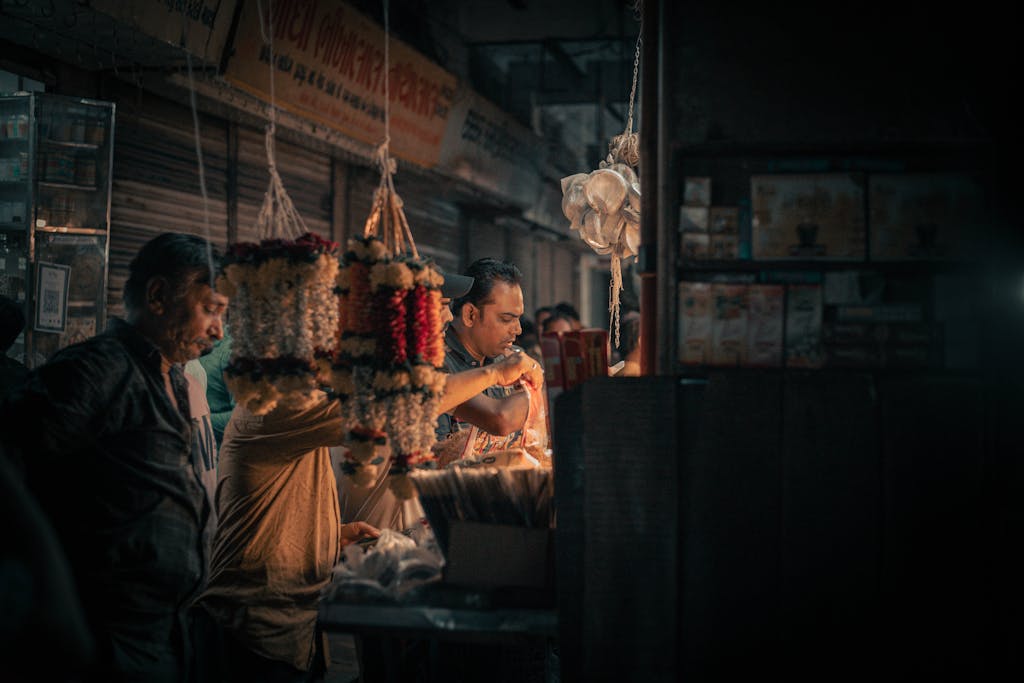 R6 Market Place An atmospheric shot of a bustling market, featuring vendors selling flower garlands by candlelight.