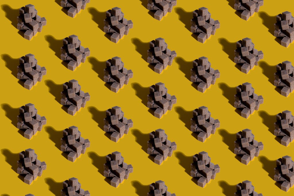 hormita Artistic arrangement of brown sugar cubes creating a modern pattern on a vibrant yellow background.