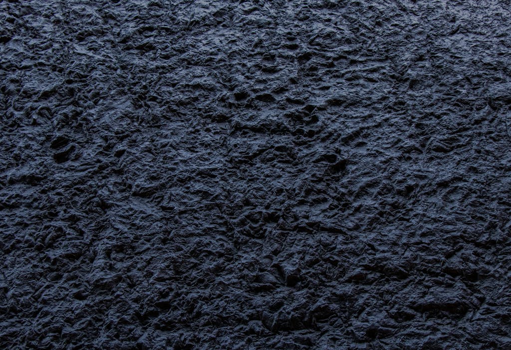 Messagenal Close-up of a dark, rough textured stone surface providing an abstract background.