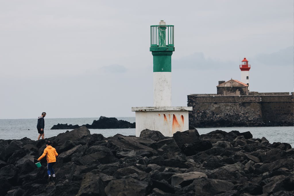 vrealize infrastructure navigator Unrecognizable people walking on rough stony breakwater with lighthouse tower in gray overcast weather on seashore