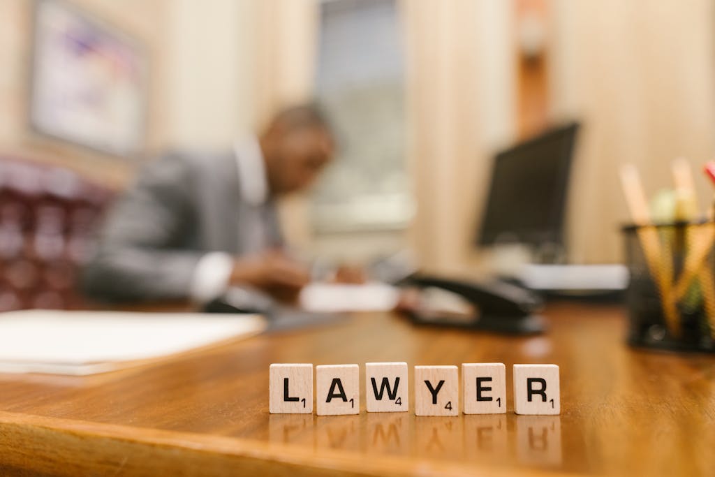 EMFYTEYMATA Wooden letter tiles spelling 'LAWYER' on a desk, with blurred office setting in the background.