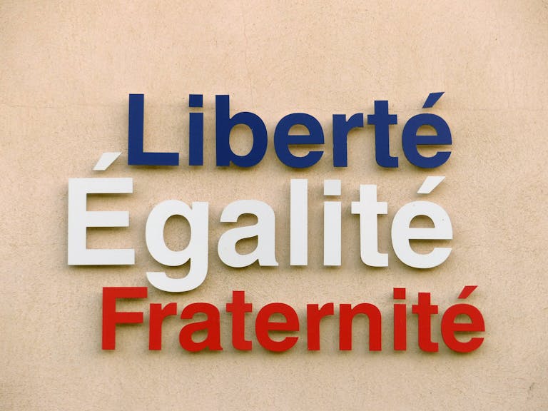 IPLLeague2026 Bold text of 'Liberté, Égalité, Fraternité' on a wall in France.